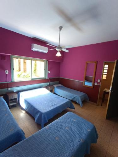 a bedroom with three beds and purple walls at Hotel Paris in Buenos Aires