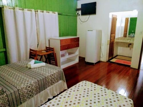 a room with two beds and a sink and a refrigerator at Pousada Bosque dos Aruãs in Salvaterra