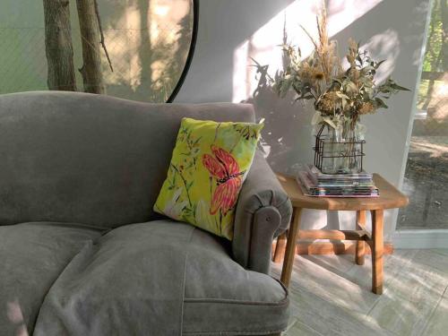 a grey couch with a vase of flowers on a table at Loft moderno en medio del bosque in Arturo SeguÃ­