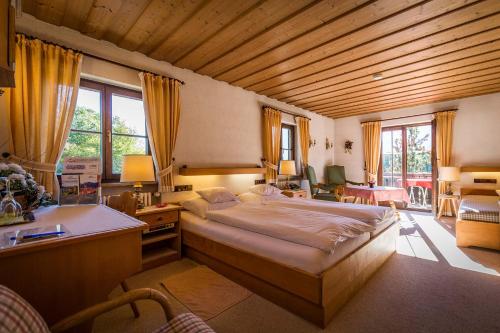 a bedroom with a large bed and a desk at Landhotel Sonnleiten in Bad Reichenhall
