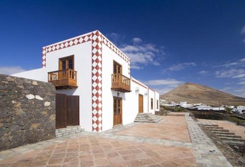 ein weißes Haus mit einem Balkon und einem Berg in der Unterkunft Sehr großzügig und modern eingerichtetes Ferienhaus mit privatem Pool und Sonnenterrassen im eigenen Garten in Tías