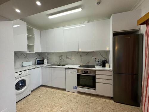 a kitchen with white cabinets and a stainless steel refrigerator at Sofiamarholidays - Casa Praia Mar in Portimão