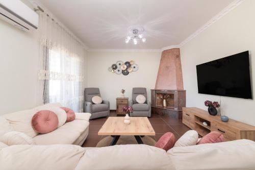 a living room with white furniture and a flat screen tv at Villa Olympia in Pandokrátor