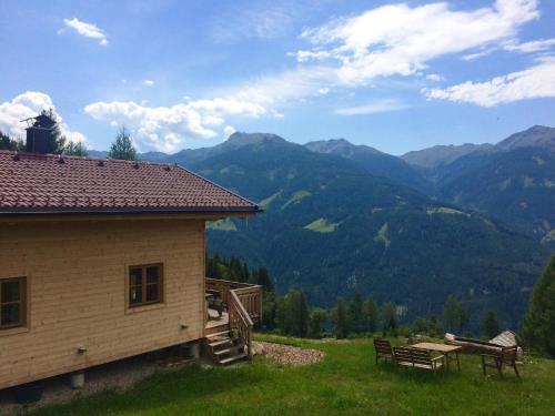 a building with a picnic table and mountains in the background at Gemütliche Berghütte mit Sauna in beeindruckender Höhenlage in Rangersdorf