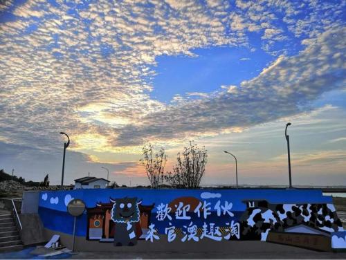 um mural de um gato numa parede com um céu em Ba Ba Guan Hai Ancient House B&B em Jinsha