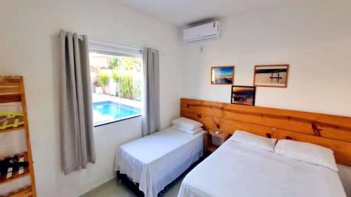 1 dormitorio con 2 camas y una ventana con piscina en Casa confortável tudo para seu bem-estar., en Porto Seguro