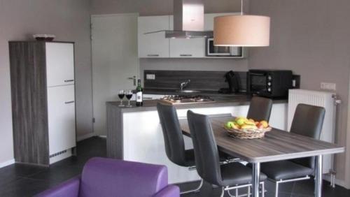 una cocina con mesa y sillas con un bol de fruta. en Modern eingerichteter Bungalow - b56111, en Oostrum