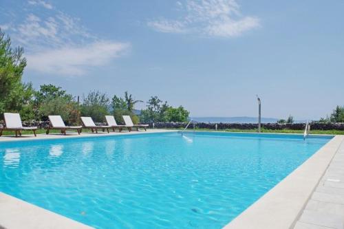 een groot zwembad met stoelen en blauw water bij Appartement in Rakalj mit gemeinsamem Pool, Terrasse und Grill in Rakalj