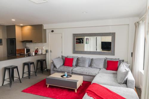 a living room with a grey couch and red pillows at Entire Apartment 21st Floor Queen Street in Auckland