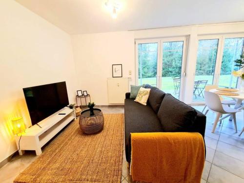 a living room with a couch and a tv at Spacious one bedroom with garden&balcony in Pulvermühle