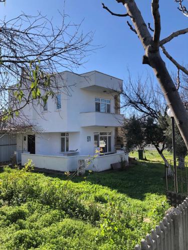 uma casa branca com uma cerca num quintal em Bozcaada Manzaralı Müstakil Bahçeli Aileye Uygun Villa em Canakkale