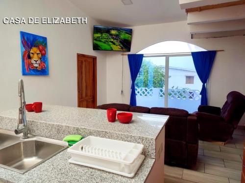 a kitchen with a sink and a living room at Casa de Hamacas in Ballenita