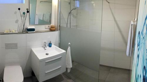 a white bathroom with a sink and a shower at Ferienapartment am Möhnesee in Möhnesee
