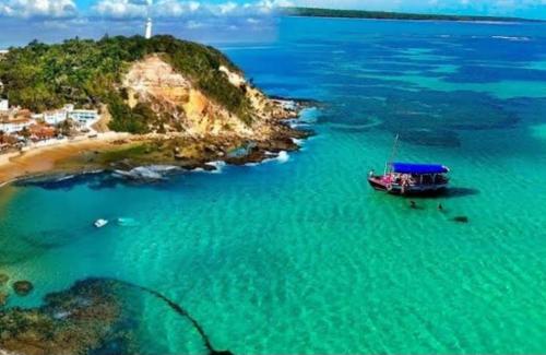 a boat in the water next to a small island at Loft Morro de São Paulo in Cayru