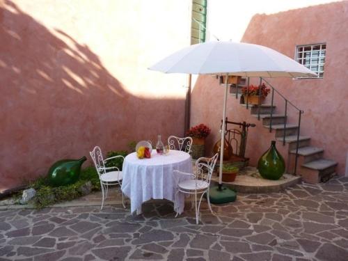 uma mesa e cadeiras com uma mesa branca e um guarda-sol em Große Ferienwohnung in Bargecchia mit Kleinem Balkon em Corsanico-Bargecchia