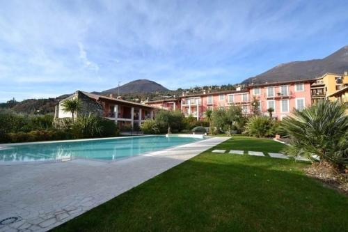 un complexe avec une piscine et des montagnes en arrière-plan dans l'établissement Stilvolle Wohnung in Toscolano Maderno mit Kleiner Terrasse, à Toscolano Maderno