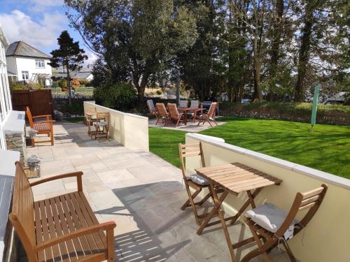 a patio with chairs and tables and a lawn at Chandler's Lodge B&B in Camelford