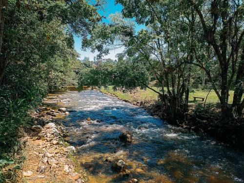 einem Wasserlauf mit Bäumen an der Seite in der Unterkunft Cabana com cachoeira no quintal in Antônio Carlos