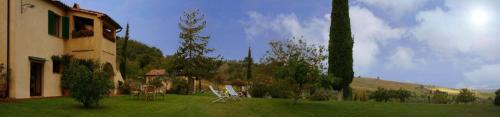 un patio con sillas, una casa y árboles en Ferienwohnung für 4 Personen ca 80 qm in Castiglione d'Orcia, Toskana Provinz Siena, en Campiglia dʼOrcia