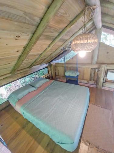 a bed in a room with a wooden ceiling at Suíte com cachoeira no quintal in Antônio Carlos