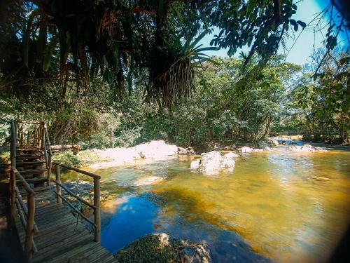 einen Fluss mit einem hölzernen Gehweg neben einer Brücke in der Unterkunft Cabana com cachoeira no quintal in Antônio Carlos