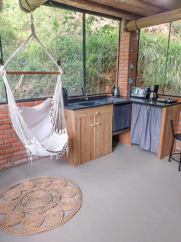 a hammock on a screened in porch with a kitchen at Suíte com cachoeira no quintal in Antônio Carlos