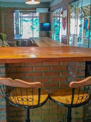 a bar with two chairs and a brick wall at Suíte com cachoeira no quintal in Antônio Carlos