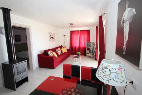 uma sala de estar com um sofá vermelho e uma televisão em Ferienhaus mit einem Schlafzimmer, Kaminofen und Sonnenterrasse em Guía de Isora