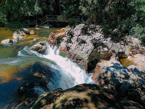 a waterfall in a river with rocks and trees at Suíte com cachoeira no quintal in Antônio Carlos