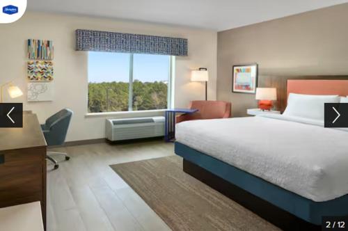 a hotel room with a bed and a desk and a window at Hampton Inn & Suites Fultondale 