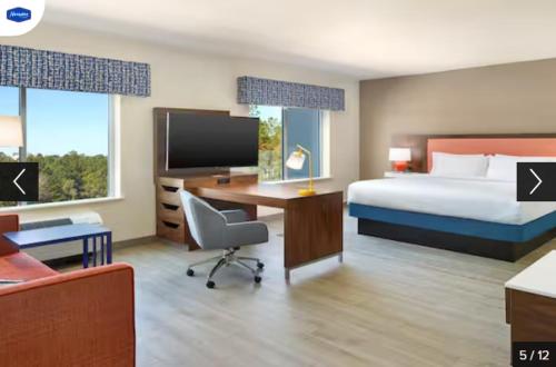 a hotel room with a bed and a desk with a computer at Hampton Inn & Suites Fultondale 