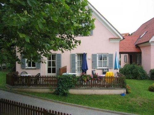 uma casa com uma cerca com guarda-chuvas no quintal em Ferienhaus in Wagerberg mit gemeinsamem Pool, Terrasse und Garten em Bad Waltersdorf