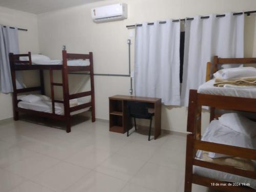 a room with two bunk beds and a table at Goiânia Hostel. in Lucas do Rio Verde
