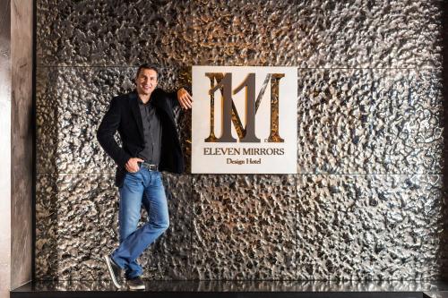 a man standing in front of a wall with a sign at 11 Mirrors Design Hotel in Kyiv