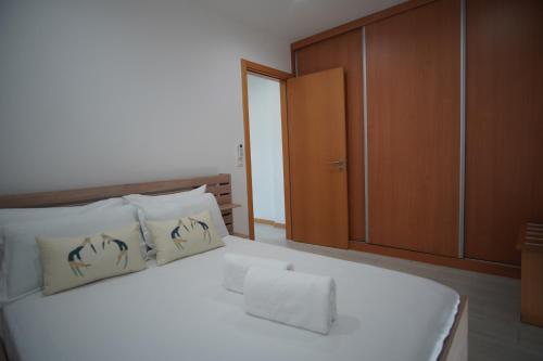 a bedroom with a white bed with a wooden cabinet at Geams Sal Suite in Santa Maria