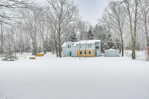 a blue house in a snow covered yard with trees at Home with Fireplace Less Than 1 Mi to Peninsula State Park! in Fish Creek
