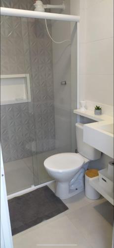 a white bathroom with a toilet and a shower at Mar Doce Lar in Santos