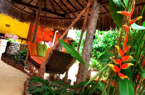 a hammock with a chair under a straw umbrella at Ibiscus Pousada sem café in Jericoacoara