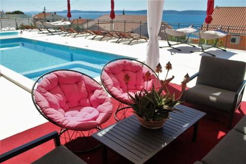 - deux chaises roses et une table à côté de la piscine dans l'établissement Helle Ferienwohnung mit Meerblick vom privaten Sonnenbalkon - b57594, à Trogir
