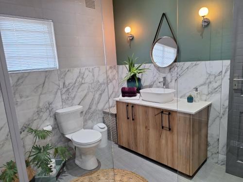 a bathroom with a toilet and a sink and a mirror at 1 CAMDEBO in Oudtshoorn