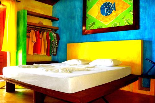 a bed in a bedroom with a blue and yellow wall at Ibiscus Pousada sem café in Jericoacoara