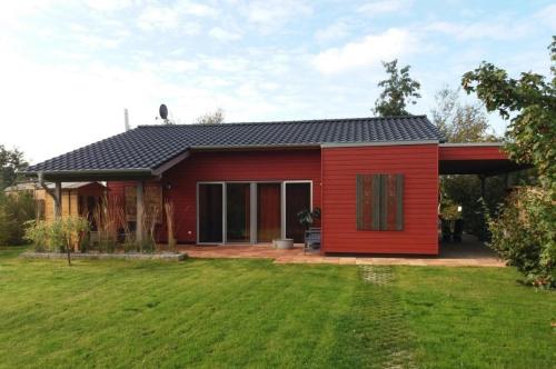una casa roja con un patio delante en Ferienhaus am kleinen See mit Steg, Garten und Terrasse en Twist