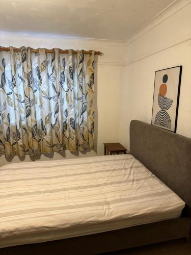 1 dormitorio con 1 cama y una ventana con cortinas en Double Rooms en Feltham