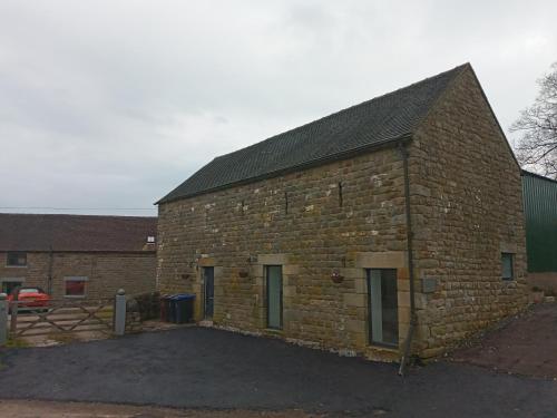 a large brick building with a gate in front of it at orchard meadow holiday barn leek-buxton-Ashbourne in Buxton