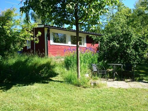 uma casa vermelha com uma mesa e cadeiras na relva em Typisches Holzhaus mit überdachter Terrasse auf weitläufigen Grundstück in einem Waldgebiet am See em Hallaryd
