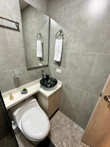 uma casa de banho com um WC, um lavatório e um espelho. em Apartamento en Laureles cerca a la 70 y Estadio - 702 em Medellín