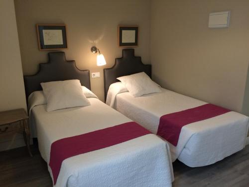 two beds in a hotel room with white and red sheets at Hotel Jávea in Jávea