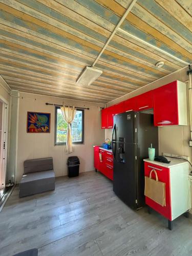 a kitchen with red cabinets and a black refrigerator at Yellow house 6 minutos de playa in Barra de Navidad