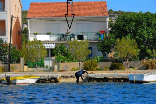un hombre de pie en la orilla del agua con barcos en Ferienwohnung für 4 Personen ca 45 qm in Poljica bei Trogir, Dalmatien Kaštela und Umgebung, en Poljica