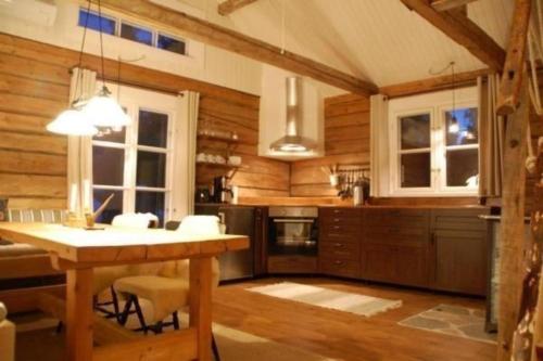 cocina con paredes de madera y mesa con sillas en Charmantes Ferienhaus in der Wildnis Lapplands en Blattnicksele